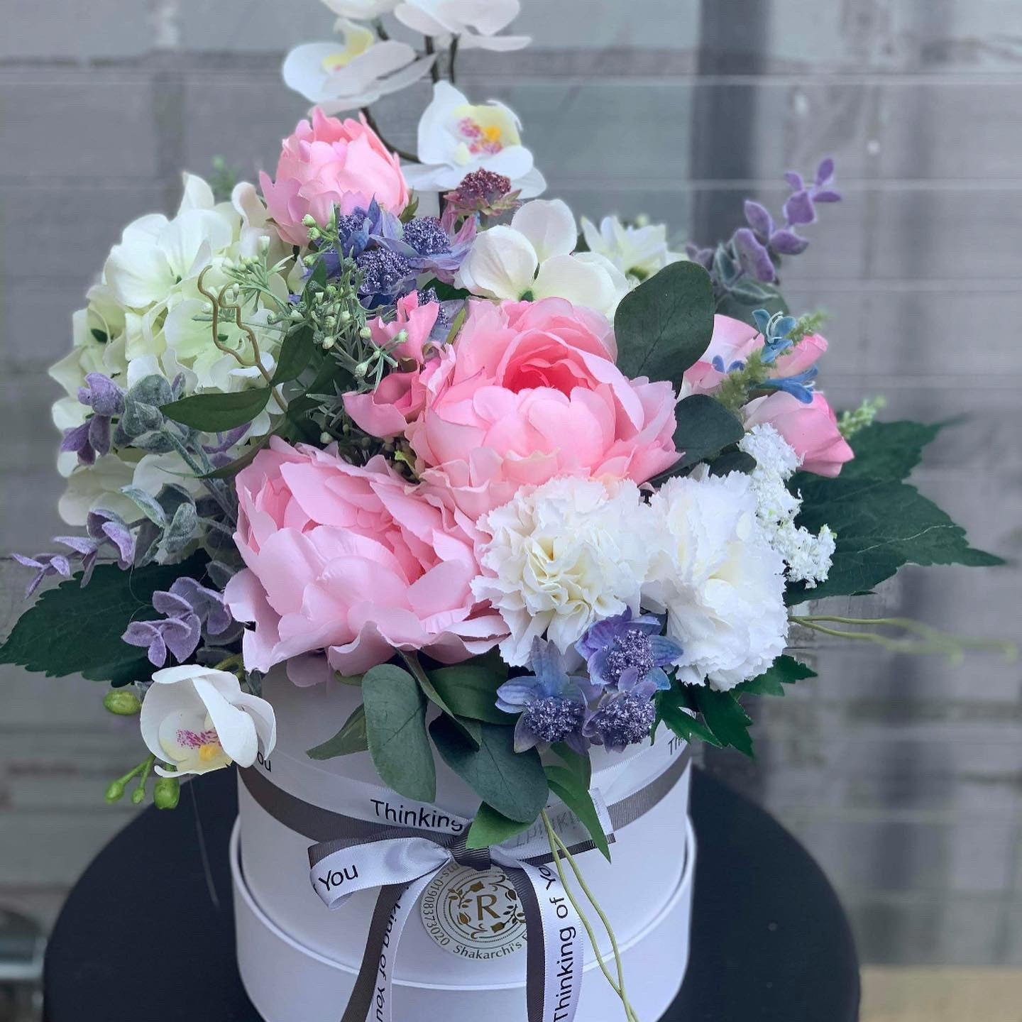 This hat box, brought to you by Rams Florist, ,A hatbox isn't just for hats, it can be for gorgeous flowers too! This beautiful box will be bursting with stunning pastel blooms, chosen and arranged by our local florist so it wows your beloved